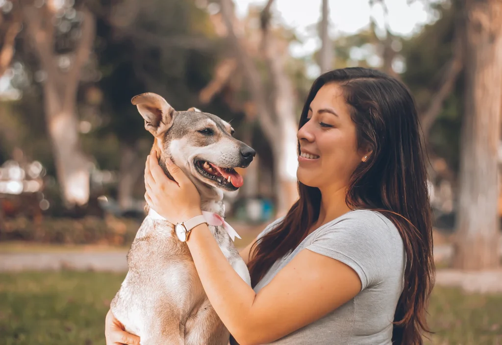 Smiling woman holding her small dog outdoors