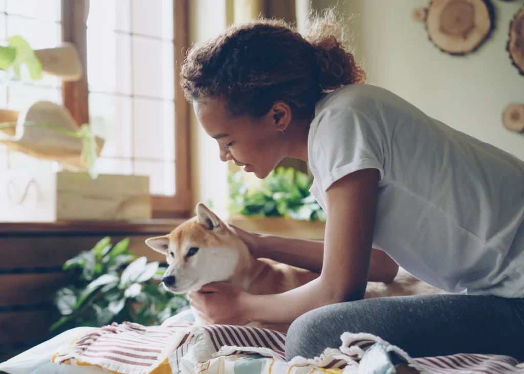 Woman cuddling a small dog at home