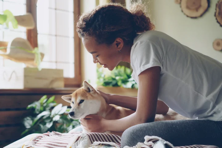 Woman cuddling a small dog at home